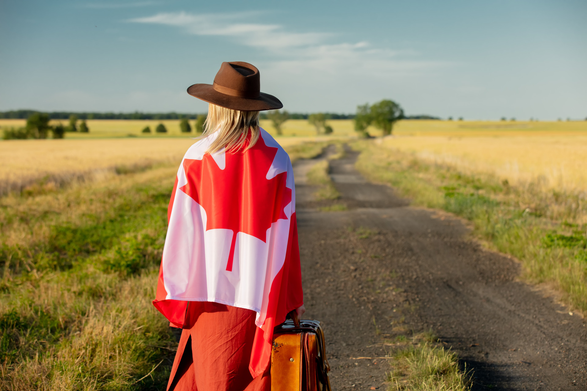 girl in canada flag with suitcase on country road