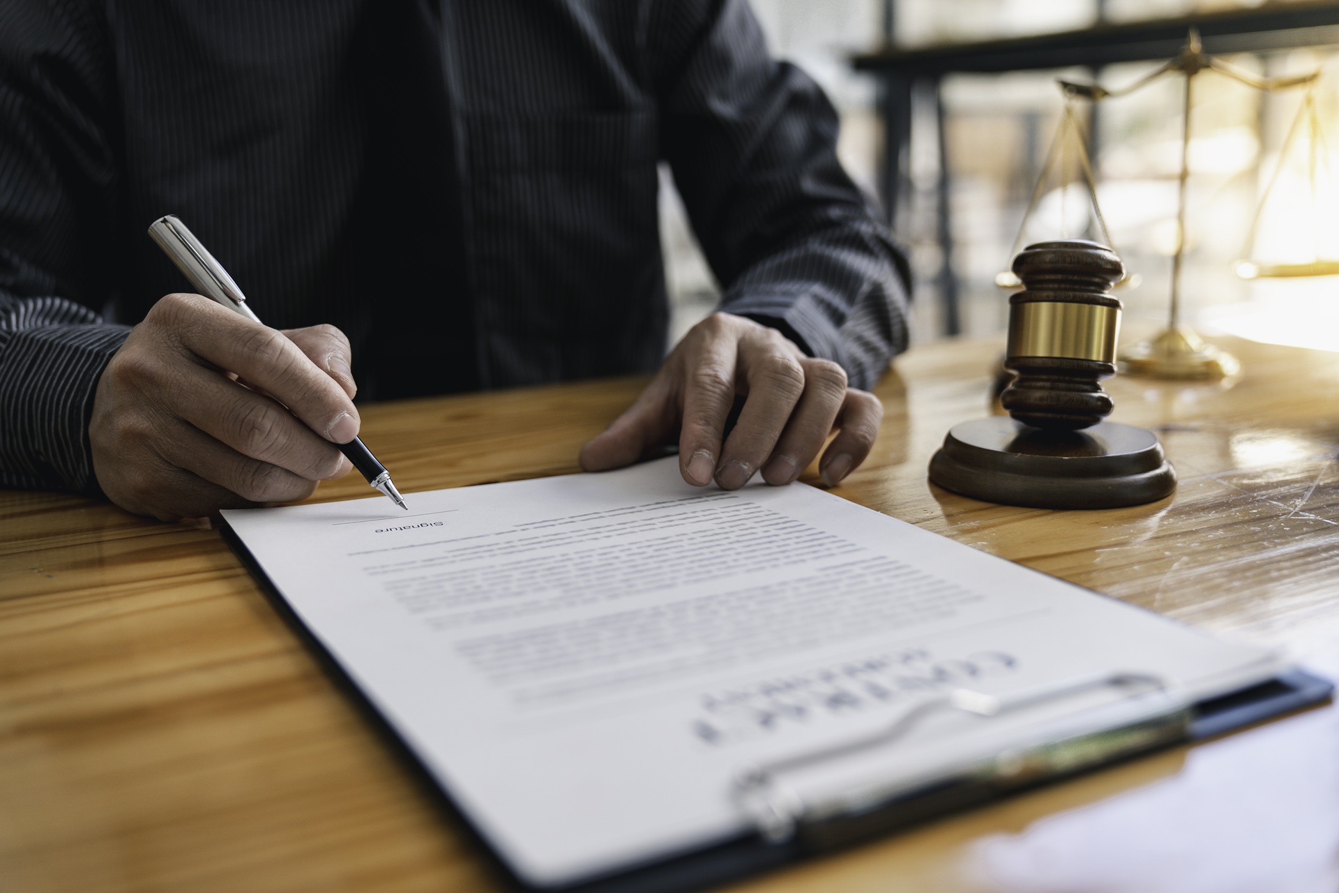 Lawyer signing legal document at office desk