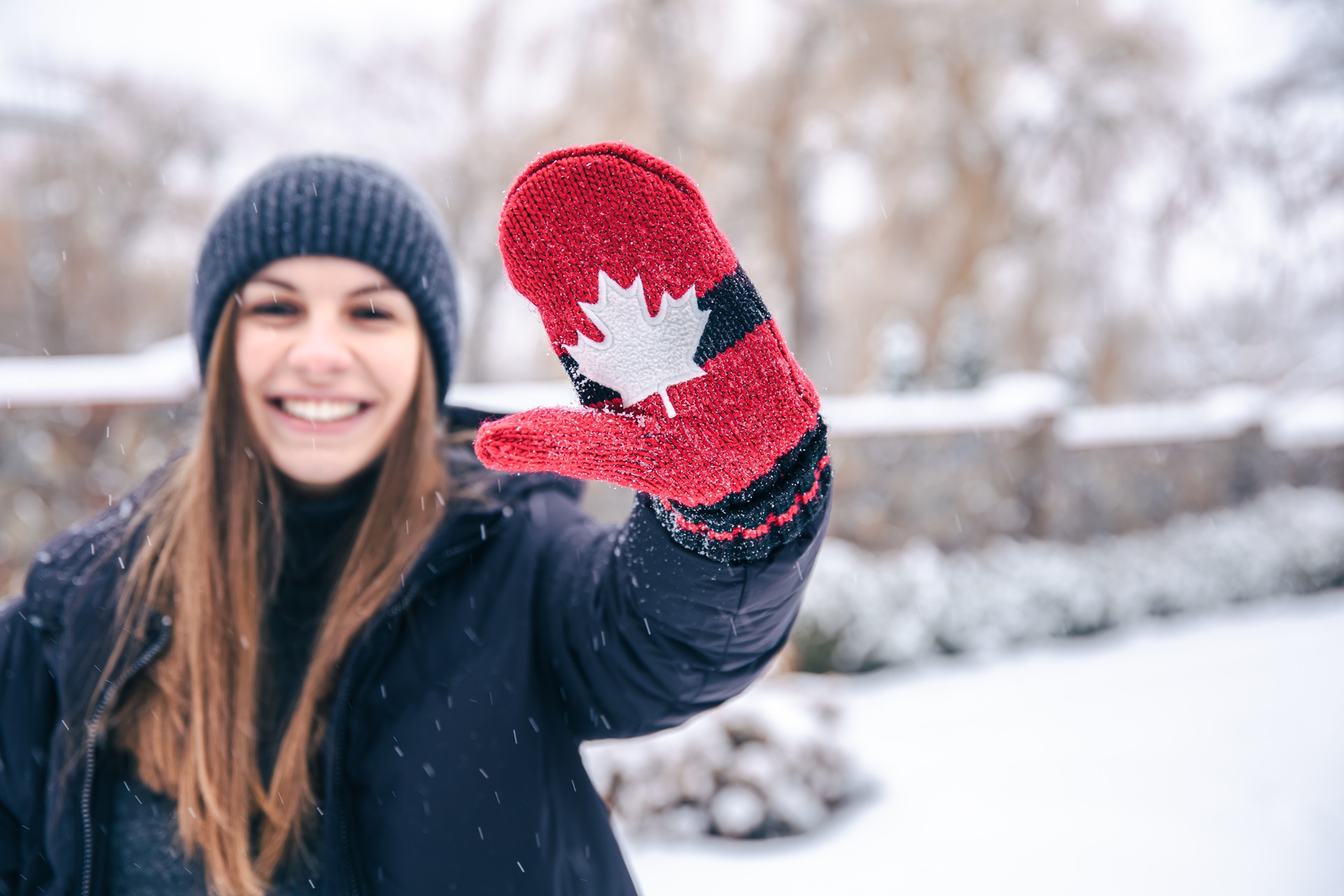 Smiling woman wearing red mittens with maple leaf