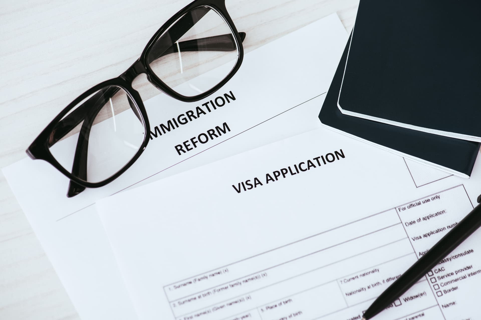 Visa application and immigration reform documents with glasses and passport