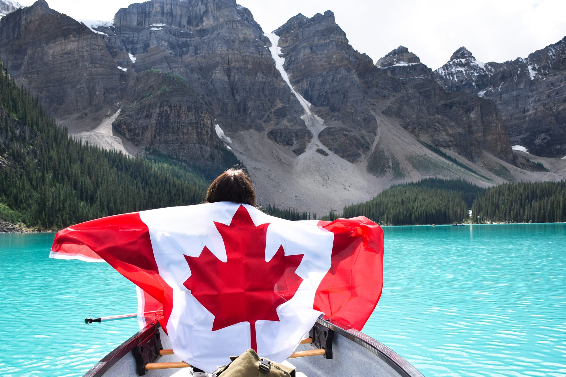 woman-with-canadian-flag-in-canoe-on-turquoise-lake