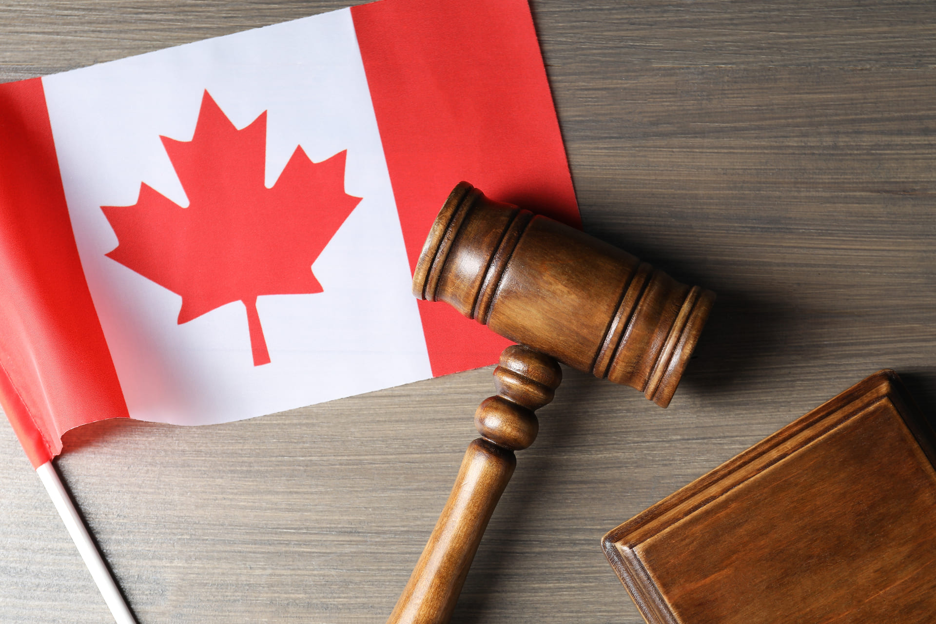 wooden-gavel-and-sound-block-next-to-a-canadian-flag