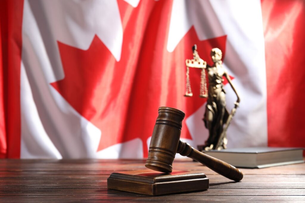 wooden-judge-gavel-and-lady-justice-statue-against-canadian flag