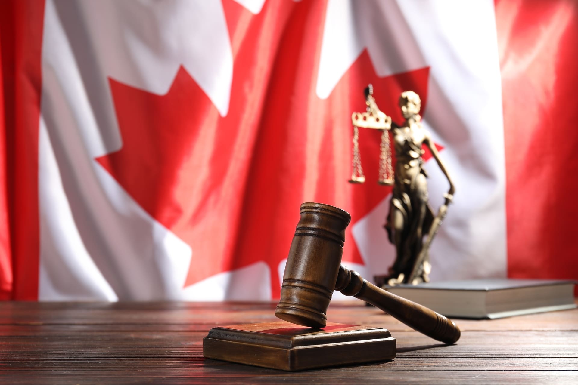 wooden-judge-gavel-and-lady-justice-statue-against-canadian flag