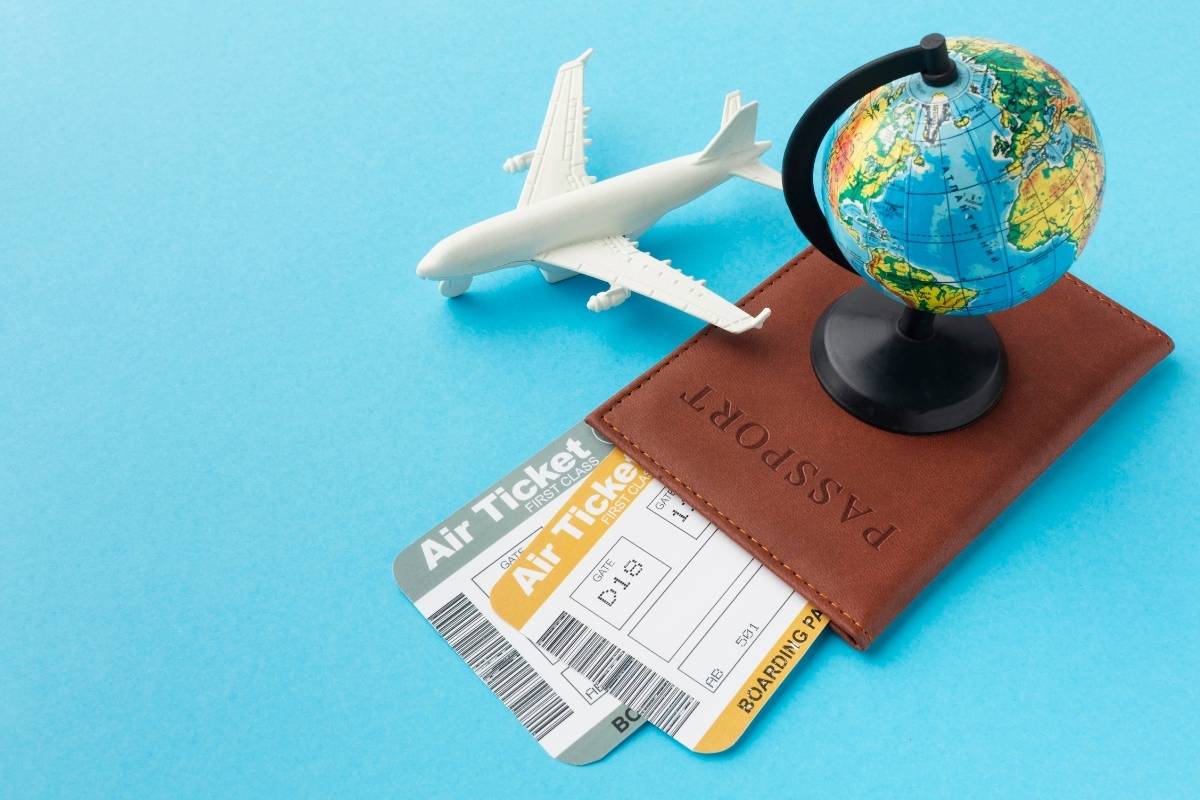 passport and plane ticket in the table with small globe and model plane